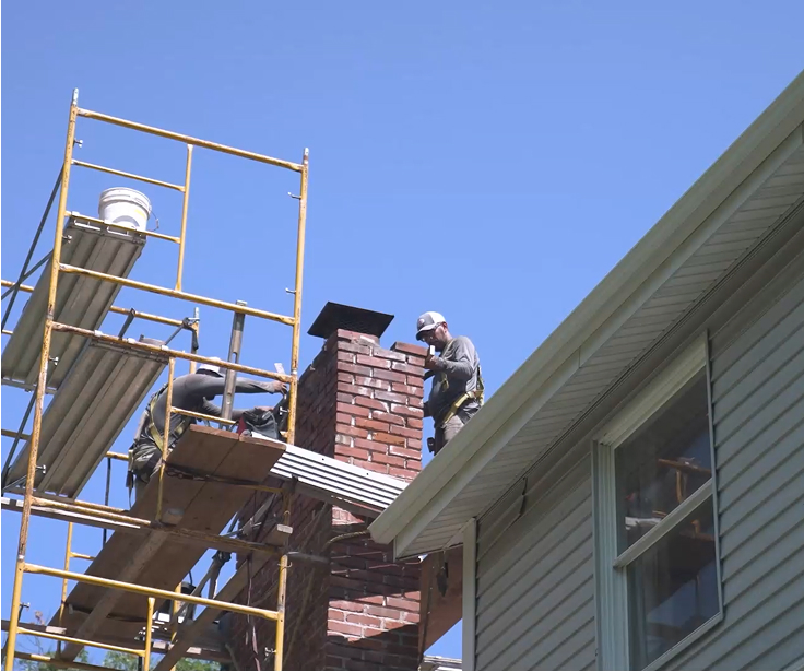 men performing chimney repair and rebuild on a brick chimney